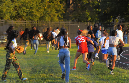 Spectators run for cover as multiple shots ring out during the kickoff of the 2023-2024 varsity football season between the Dunbar Poets and the Loyola Blakefield Dons at William F. “Sugar” Cain Field in Baltimore Friday Sept. 1, 2023. FILE (Karl Merton Ferron/Baltimore Sun Staff)