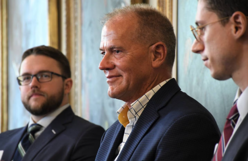 John Huffington, center, is applauded during a meeting of the Maryland Board of Public Works on July 5, 2023. The board awarded $2.9 million for being wrongly convicted and incarcerated for decades. Huffington, who was on death row, has written a book and worked for nonprofit organizations since his conviction was vacated. (Pamela Wood)